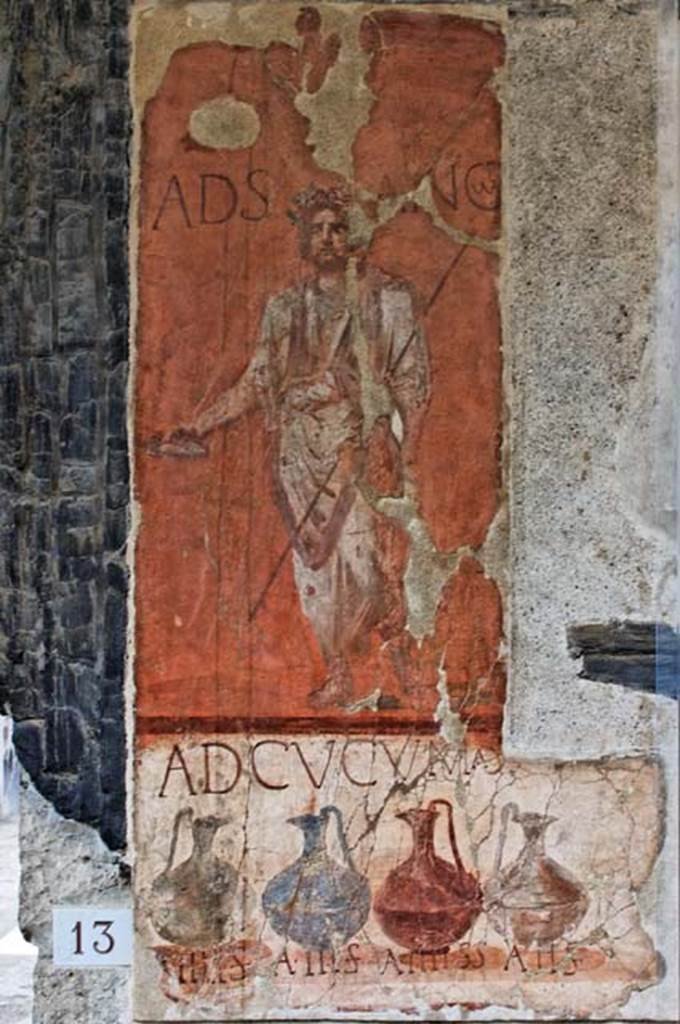 VI.13/14 Herculaneum, April 2010. Painted sign on pilaster between house entrance and shop. Looking south. Photo courtesy of Nicolas Monteix. 
According to Cooley, 
“the words ad Sancum appear painted next to an image of a bearded togate figure holding a libation dish and a staff, with his head garlanded. This figure has been interpreted as being the god Semo Sancus, associated with guaranteeing oaths.”
See Cooley, A. and M.G.L., 2014. Pompeii and Herculaneum: A Sourcebook. London: Routledge, (p.266-7, H80, (AE (1989)182c).

