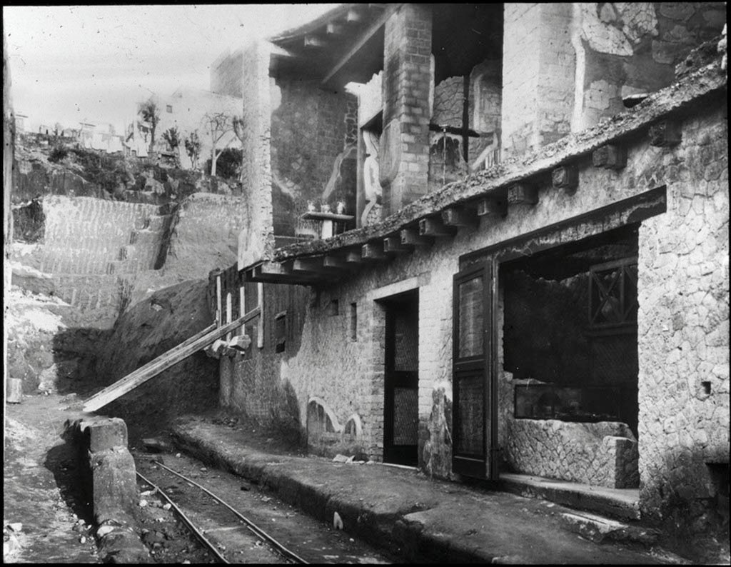 Cardo IV Superiore, Herculaneum. Looking north along Cardo IV Superiore towards Insula V., during excavations in 1935.
Photo by Fratelli Alinari (I.D.E.A.). Alinari No 43312.
V.6, the doorway to the wine/food shop is on the right.
V.7, the doorway to Casa di Nettuno e Anfitrite or House of Neptune and Amphitrite and upper floor, is in the centre.
V.8, is the area still being excavated beneath props holding wall up, on left.
Used with the permission of the Institute of Archaeology, University of Oxford. File name instarchbx116im012 Resource ID 42241.
See photo on University of Oxford HEIR database

