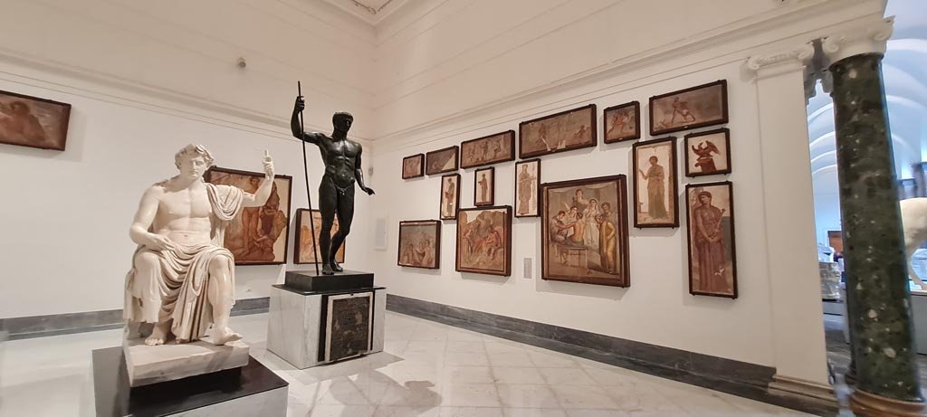 Herculaneum Augusteum. April 2023. 
Looking towards paintings on display on side wall in “Campania Romana” gallery in Naples Archaeological Museum. 
Photo courtesy of Giuseppe Ciaramella.
