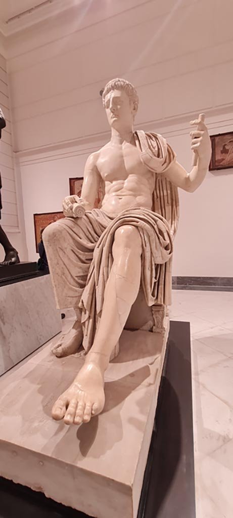 Herculaneum Augusteum. April 2023. 
White marble statue of Claudius, inv. 6056, with modern additions of the head and arms. 
Photo courtesy of Giuseppe Ciaramella.
