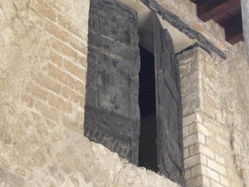 Decumanus Maximus, Herculaneum. October 2020. Detail of carbonised wood from above doorway numbered 4, and wooden shutter.
Photo courtesy of Klaus Heese.
