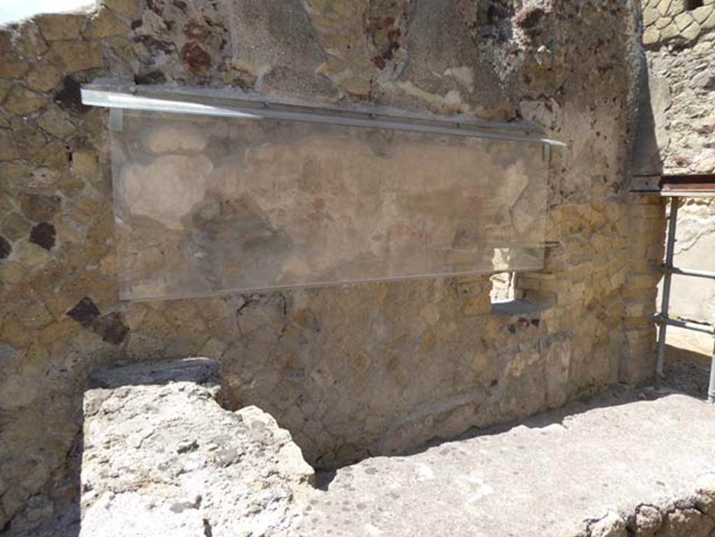 IV.17, Herculaneum, July 2015. Looking south towards the remains of the Priapus figure painted on the wall behind the sales counter.  Photo courtesy of Michael Binns.
