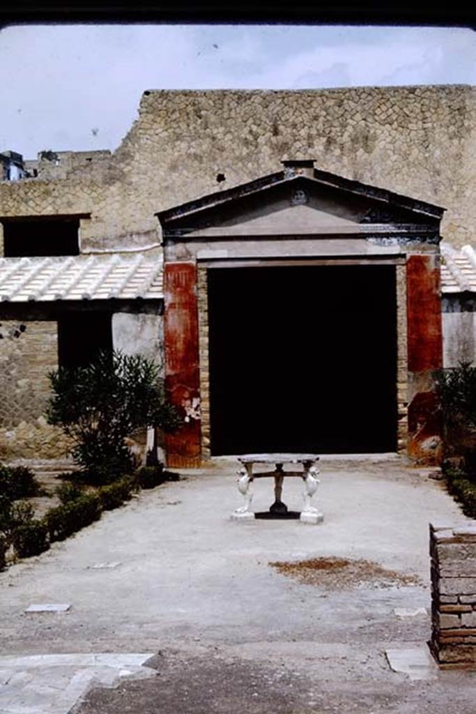 IV.21, Herculaneum. 1964. 
Looking north across garden area towards the great portal. Photo by Stanley A. Jashemski.
Source: The Wilhelmina and Stanley A. Jashemski archive in the University of Maryland Library, Special Collections (See collection page) and made available under the Creative Commons Attribution-Non-Commercial License v.4. See Licence and use details.
J64f1423

Maiuri wrote that the garden, closed between the walls of the quadriporticus and adorned with marble tables and sculptures, is still adorned at the triclinium end by a great portal with a pediment once entirely reveted with glass paste mosaic, with a head of Oceanus in the centre of a frieze of Cupids on seahorses.
See Maiuri, Amedeo, (1977). Herculaneum. 7th English ed, of Guidebooks to the Museums Galleries and Monuments of Italy, No.53 (p.60-63).
