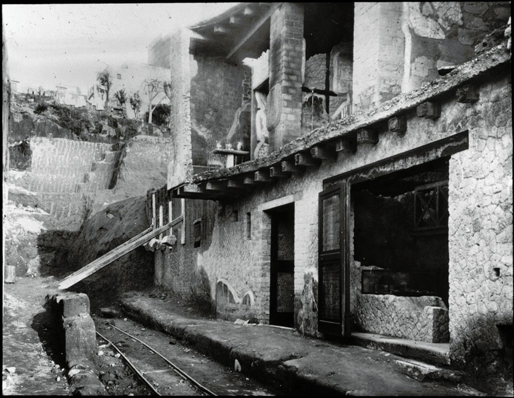 Cardo IV Superiore, Herculaneum. Looking north along Cardo IV Superiore towards Insula V., during excavations.1935.
Photo by Fratelli Alinari (I.D.E.A.). Alinari No 43312.
V.6 the doorway to the wine/food shop is on the right.
V.7, the doorway to Casa di Nettuno e Anfitrite or House of Neptune and Amphitrite, is in the centre.
V.8, is the area still being excavated beneath props holding wall up, on left.
Used with the permission of the Institute of Archaeology, University of Oxford. File name instarchbx116im012 Resource ID 42241.
See photo on University of Oxford HEIR database
