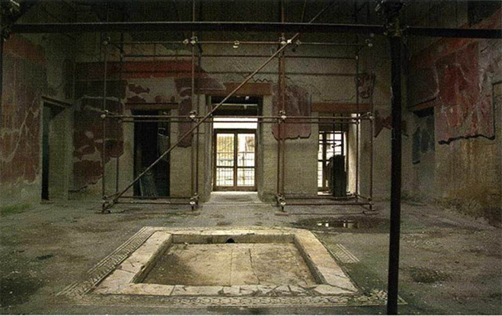 Ins. V.15 Herculaneum, House of Bicentenary, 2005. Looking across atrium towards entrance doorway.  Photo courtesy of Andrew Wallace-Hadrill.
According to Maiuri, 
The vestibule and entrance fauces lead into a wide square atrium with compluviate roof (the main beams have been put back into the original place again);
the beautiful pavement in mosaic with simple white tesserae on the black ground preserves around the marble impluvium, a band with the motive of tresses; the walls are painted a beautiful red-porphyry.
See Maiuri, Amedeo, Herculaneum. 7th English ed, of Guide books to the Museums Galleries and Monuments of Italy, No.53 (p.46)
