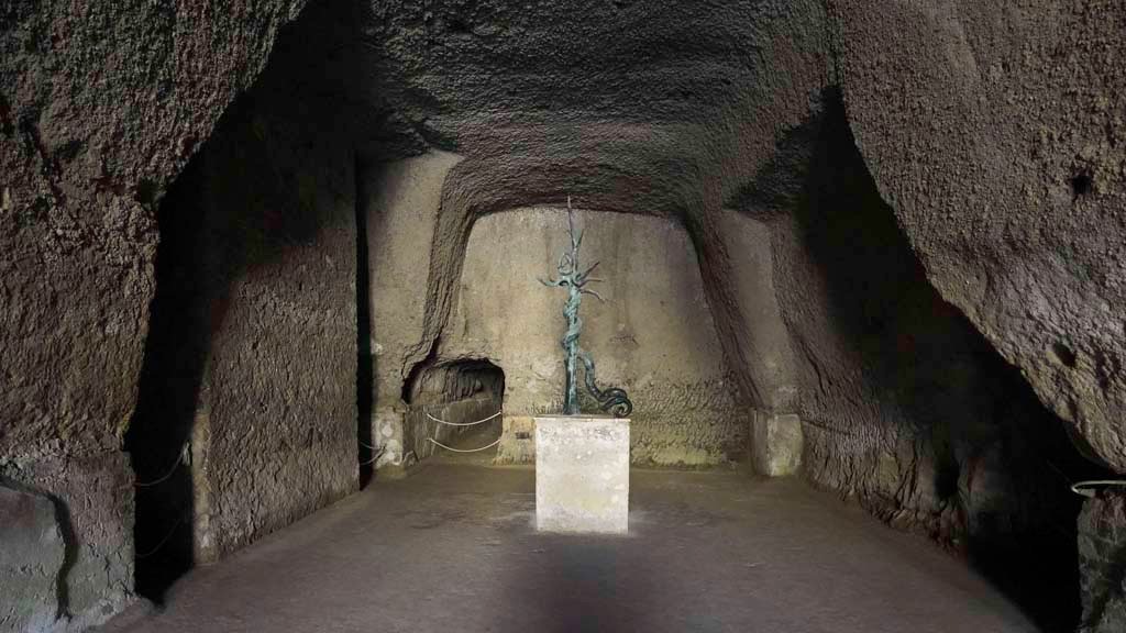 Ins. Orientalis II.4, Herculaneum, August 2021.  
Looking into the cavern, which would have been the site of the playing field of the Palaestra. Photo courtesy of Robert Hanson.
According to Deiss, 
“In the centre of the field was a swimming pool in the form of a cross, some 160 feet in length and with an intersecting arm of 100 feet.
At the ends were fountain jets. In the centre was a giant bronze serpent, coiled on the limbs of a tree, and from whose five crowned heads water sprayed into the pool. The serpent, which was overlooked by the Bourbons, has been restored to its commanding position.
The mountain of hard mud has not been removed from above the cruciform pool, but merely hollowed out like a cavern over the central portion.”
See Deiss, J.J. (1968). Herculaneum: a city returns to the sun. London, History Book Club, (p.128).
