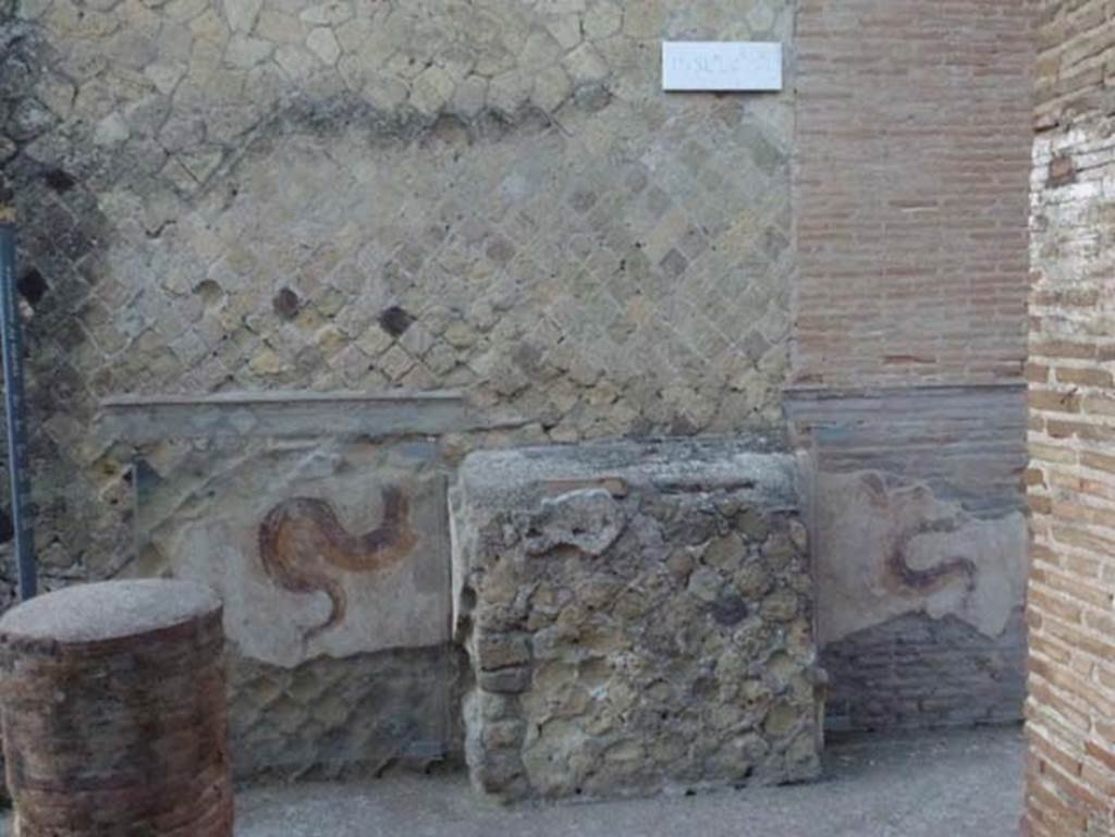 Cardo IV, Herculaneum. October 2012. North-east corner of Ins. VI. 
Looking towards west wall, with street altar and remains of two painted serpents. Photo courtesy of Michael Binns.
Herculaneum VI. East facade at the north end. 
Dimensions: Altar: H 1.22 m; W 1.23 m; D 0.45 m. Right fragment: W 0.90 m. Left fragment: W 0.96 m. 
To: Two moderately to heavily faded fragments. 
White-ground wall surface, in front of it a brick altar in the middle. The white plastered altar is flanked by two yellow-brown snakes painted on the wall to the left and right, which wind up between plants and probably have lowered their heads (now destroyed) over the altar. 
Dating: Late Third or Fourth Style.
See Fröhlich, T., 1991. Lararien und Fassadenbilder in den Vesuvstädten. Mainz: von Zabern, F73, p. 340.

