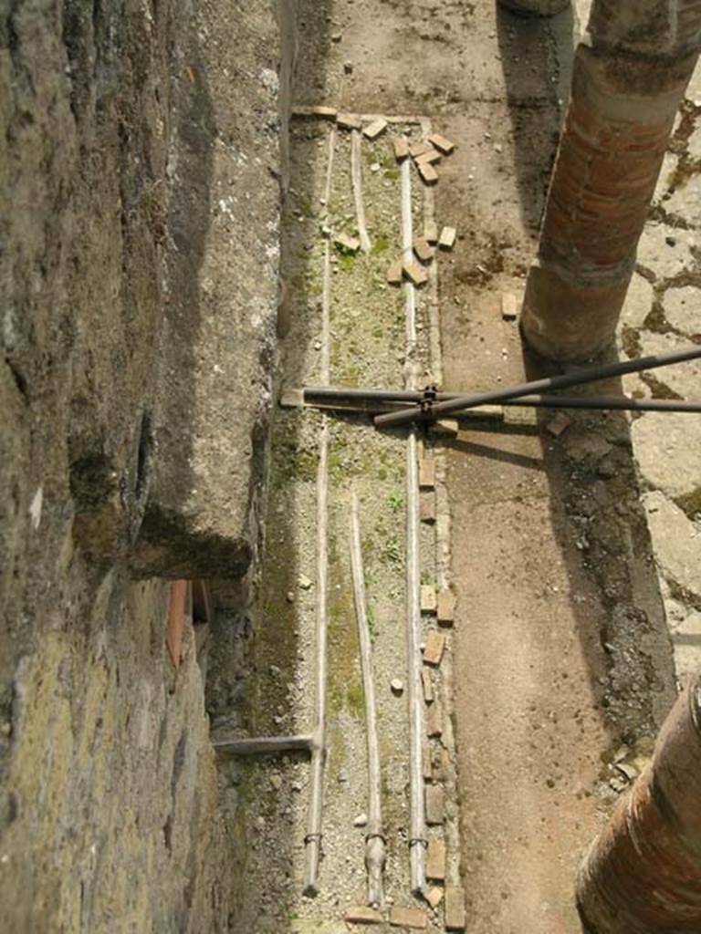 Cardo IV, Herculaneum. May 2005. 
Looking down on lead pipes in pavement of east side at north end, outside of V.9. 
Photo courtesy of Nicolas Monteix.
