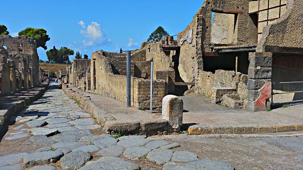 Cardo V, on left, Herculaneum, photo taken between October 2014 and November 2019. 
Looking south down Cardo V, from its junction at the north end with Decumanus Maximus. On the corner is V.21.  
Photo courtesy of Giuseppe Ciaramella.

