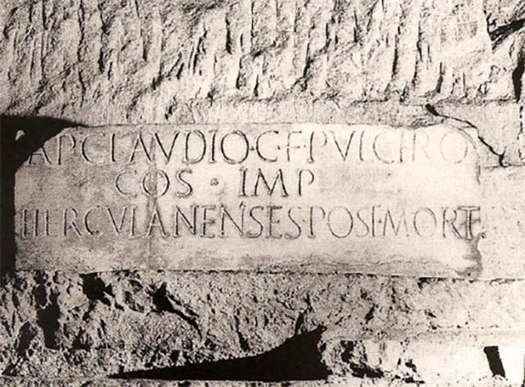 Herculaneum Theatre. Copy of inscription to AP Claudio C F Pulchro after his death, in situ underground.
Ap(pio) Claudio C(ai) f(ilio) Pulchro
co(n)s(uli) imp(eratori)
Herculanenses post mort(em)   [CIL X 1424]

According to Cooley and Cooley, this translates as
To Appius Claudius Pulcher, son of Gaius, consul, hailed victorious commander. The people of Herculaneum after his death.
See Cooley, A. and M.G.L., 2014. Pompeii and Herculaneum: A Sourcebook. London: Routledge, D65, p. 94.
This inscription, opposite that for M. Nonius Balbus, may mark the place where an honorific chair was set up in memory of Appius Claudius Pulcher.
A second honorific chair was set up for Marcus Nonius Balbus.

Another, earlier, inscription was found on an architrave.
Appius Pulcher C(ai) f(ilius) co(n)s(ul) imp(erator) VIIvir epulon(um)   [CIL X 1423]

According to Cooley and Cooley, this translates as
Appius Pulcher, son of Gaius, consul, hailed victorious commander, one of the board of seven for feasting.
See Cooley, A. and M.G.L., 2014. Pompeii and Herculaneum: A Sourcebook. London: Routledge, D64, p. 93.

“The other statue base with inscription, above, is dedicated to Appius Claudius Pulcher, who was consul in the year 38 B.C.”.
See Maiuri, A, (1977). Herculaneum, (p.74).

Corti wrote – “Finally, there was an enormous marble slab, about five feet high and fifteen feet long. This was laboriously moved until it could be wound up the well on a windlass, and when it was cleaned it was found to have great letters, almost a foot tall, let into it in metal. It was an inscription in Roman capitals, bearing the name of Appius Pulcher, son of Caius, who lived about 38BC., in the year when Caius Norbanus Flaccus was Roman consul. Pulcher was in correspondence with Cicero and succeeded him as governor of Sicily”.
See Corti, E.C.C. (1951). The Destruction and Resurrection of Pompeii and Herculaneum, London, Routledge & Kegan Paul, (p.102)
