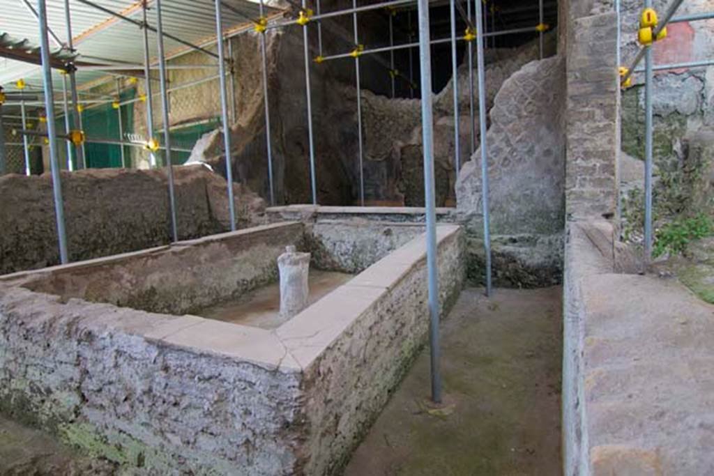 House of Dionysiac Reliefs, Herculaneum. July 2010. 
In room (p) a fountain and pool has been found, provided with a rectangular masonry basin with upper border edged with marble, at the centre it had a masonry column pierced by a lead pipe/tube, coming from the adjoining room (l3), overlooked by a large window onto this area.  
Looking north across rectangular basin of pool towards window. On the right, east, is a window into room (m).
Photo courtesy of Michael Binns.


