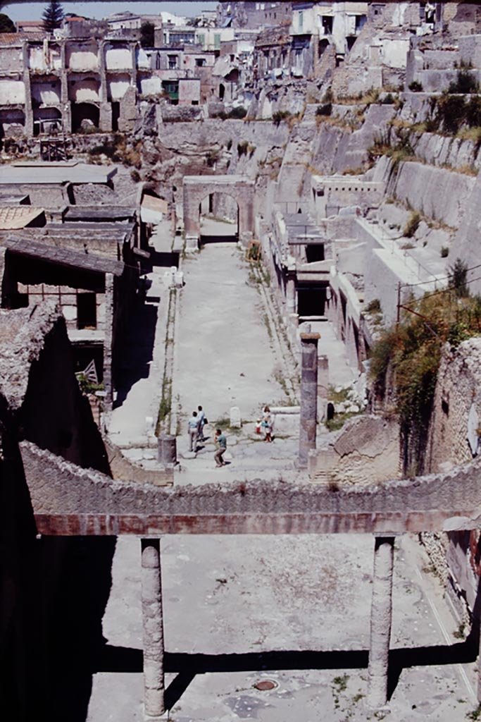 Looking west along Decumanus Maximus, Herculaneum, 1968, from the access bridge/roadway. 
The drainage channels and fountains can be seen on both sides of the road. Photo by Stanley A. Jashemski.   
Source: The Wilhelmina and Stanley A. Jashemski archive in the University of Maryland Library, Special Collections (See collection page) and made available under the Creative Commons Attribution-Non Commercial License v.4. See Licence and use details.
J68f1820

